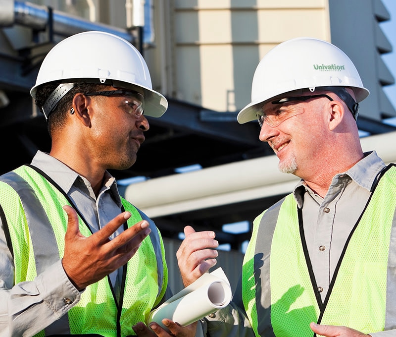 Multiracial male workers having discussion near power generator. (age 40s and 50s).